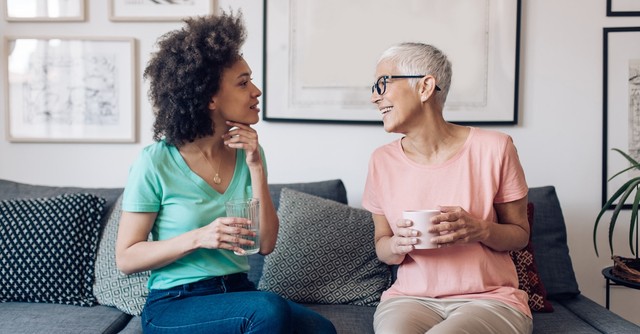 Senior woman talking with adult woman on couch