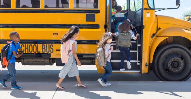 A line of elementary students getting on a school bus