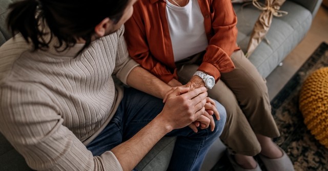 Adult son and mom talking on couch apologizing forgiving reconciliation