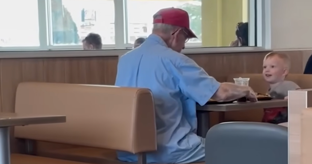 a toddler sitting with an elderly man in a McDonald's booth