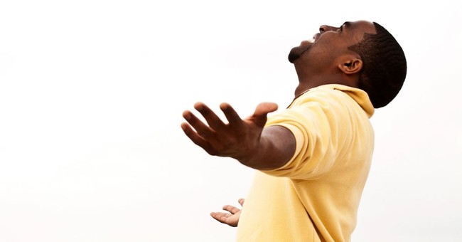 man with arms out wide, smiling, head back towards sky in praise