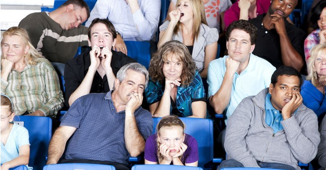 pan shot of variety of folks in audience looking unimpressed and bored
