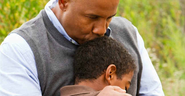 father hugging son and kissing him on top of head benediction