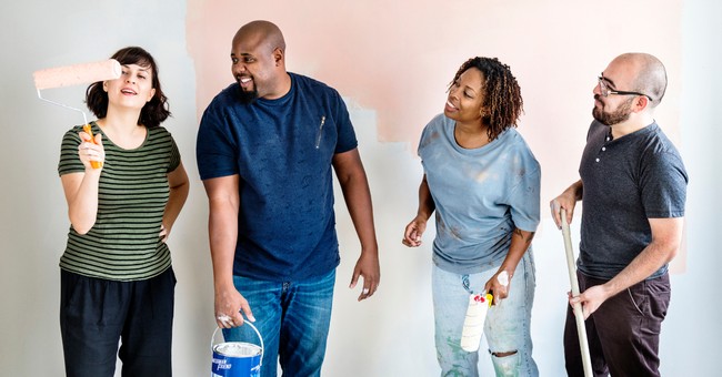 four adults painting wall together