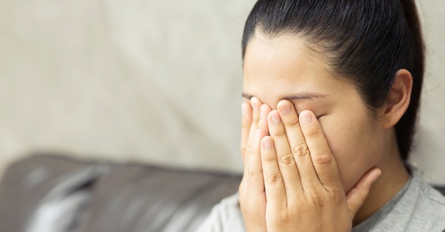 woman covering face sad to see what she is watching