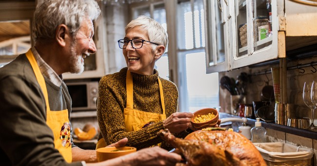 Senior couple happy laughing cooking together for Thanksgiving in kitchen