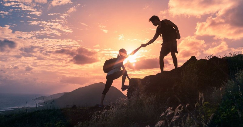 man and woman climbing a mountain together