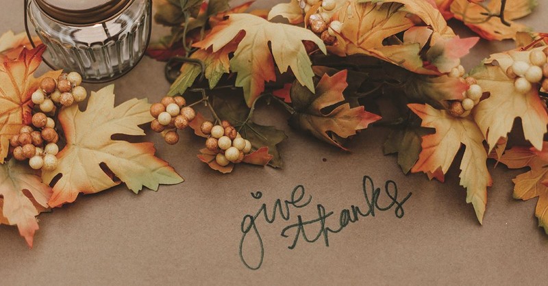 "give thanks" written on brown paper with decorative Fall leaves around for Thanksgiving