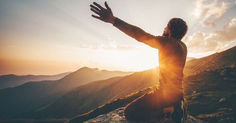 man praying on a mountain,