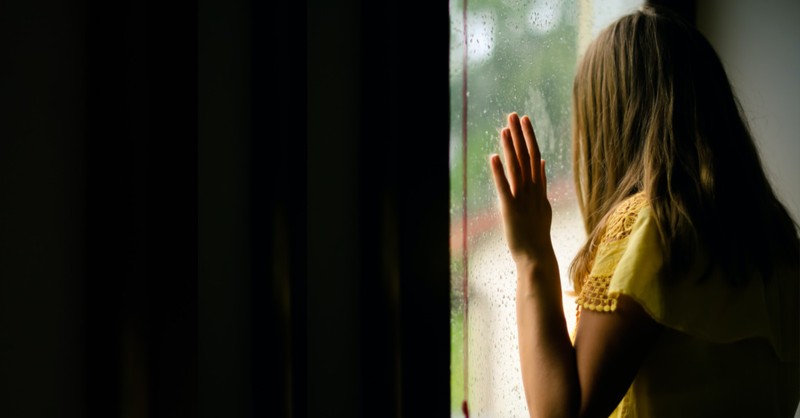 woman looking out window sad