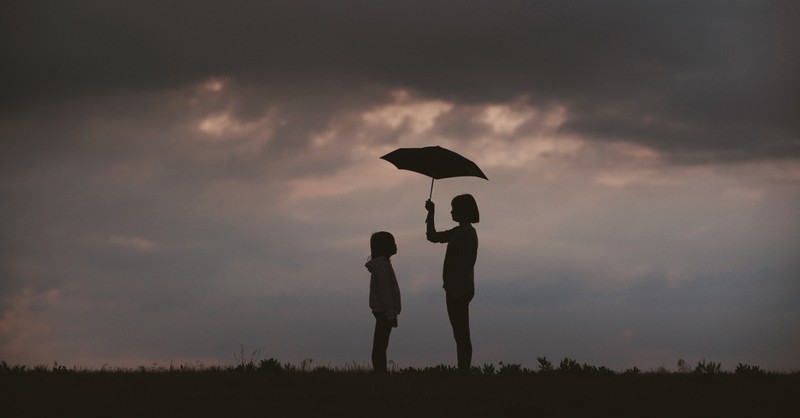 woman holding umbrella over child