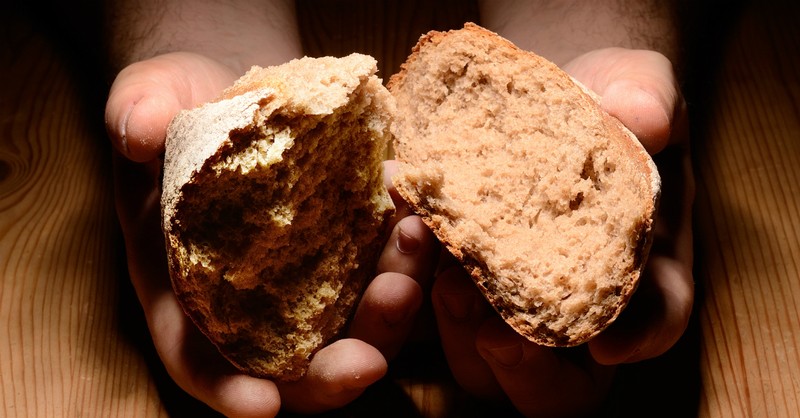 Man holding two pieces of bread, give thanks to the lord