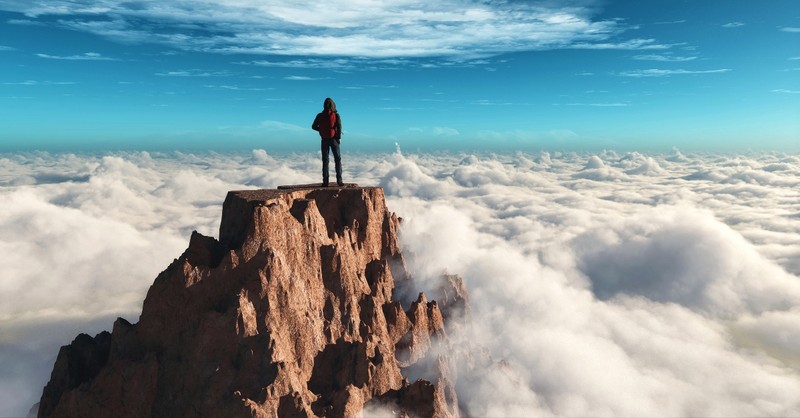 man standing on rocky peak above clouds