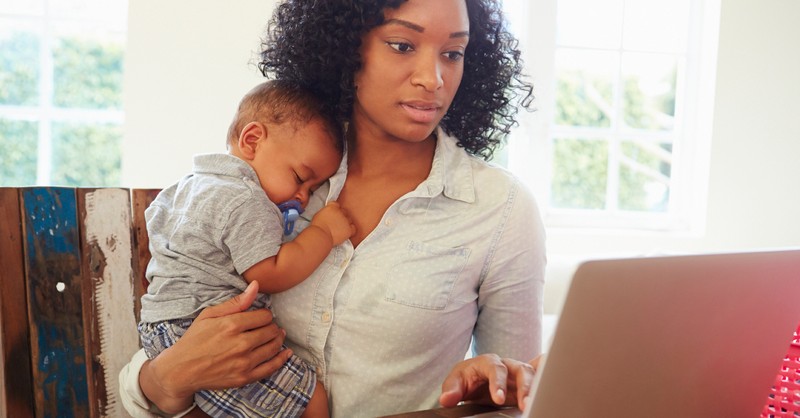 mom working while holding baby