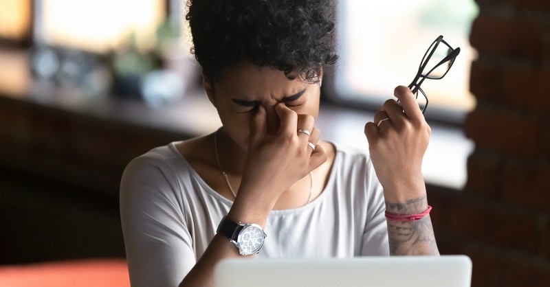 woman looking tired and stressed rubbing eyes