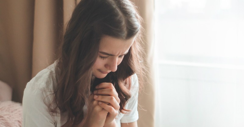 Woman praying beside a window