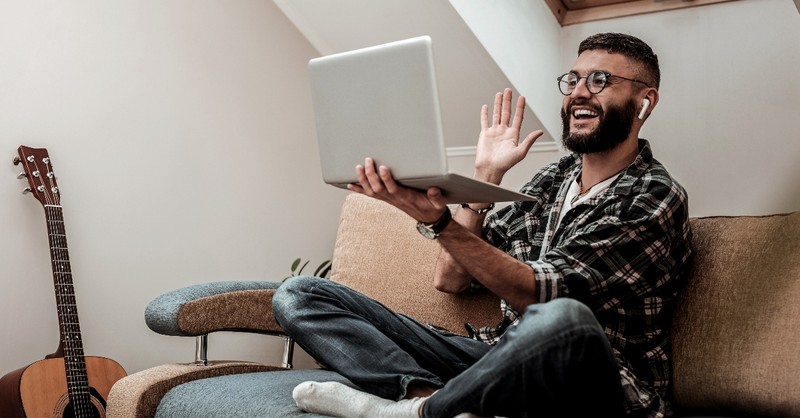 guy waving to friends on the computer