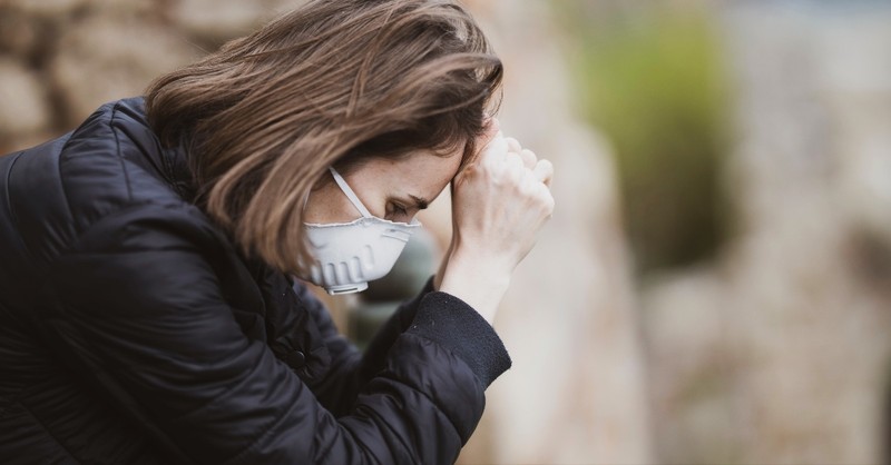 woman in mask looking overwhelmed and discouraged