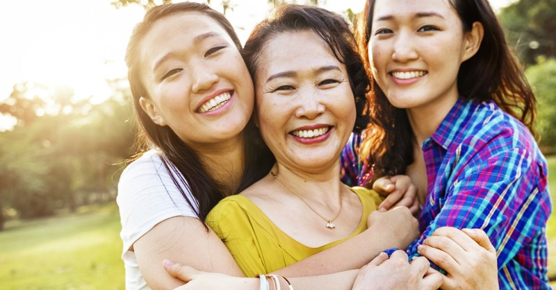 mother with two teen daughters hugging and smiling