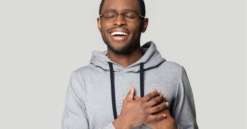 man smiling with his hands over his heart