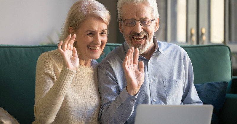 senior couple waving into laptop, empty nester