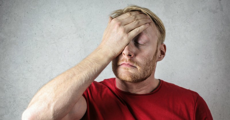 man in red shirt covering his face afraid worried fear