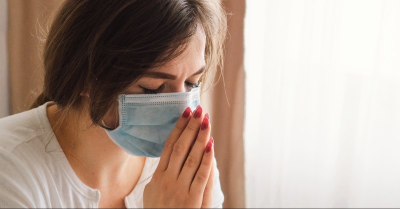 Woman with face mask on praying, clear vision hoped for 2020