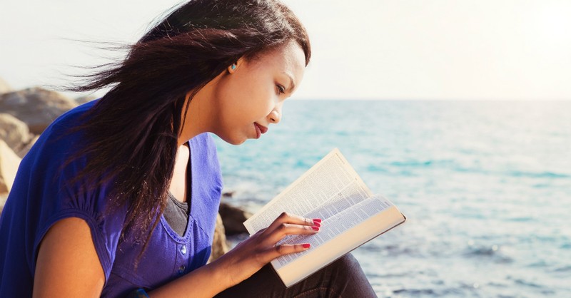 woman reading bible in purple shirt by ocean, bible verses self-care