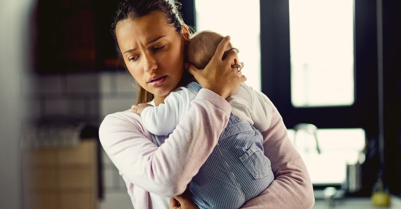 mom holding baby looking worried and stressed in kitchen, lies parents believe