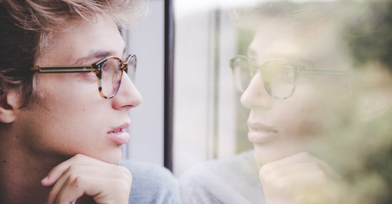 Young man looking at reflection in a window