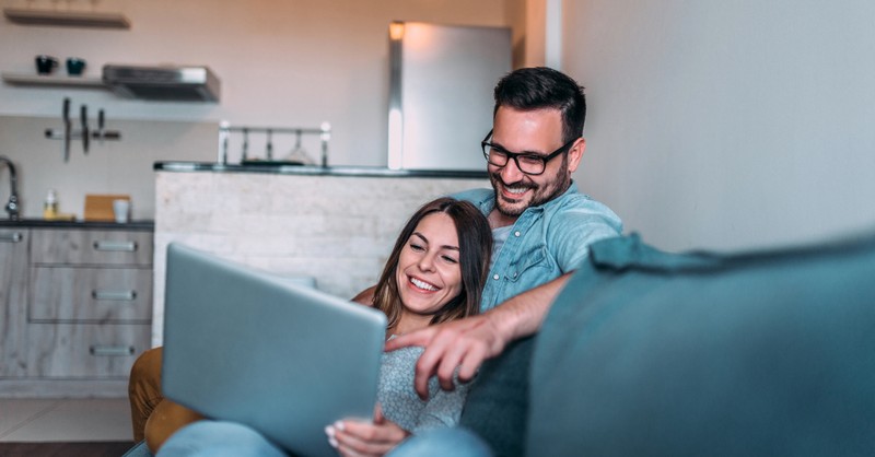 couple happily watching video on laptop together