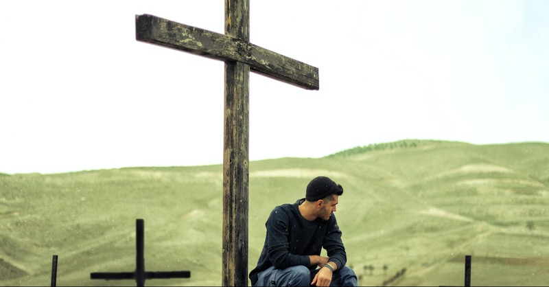 A man sitting at the foot of the cross