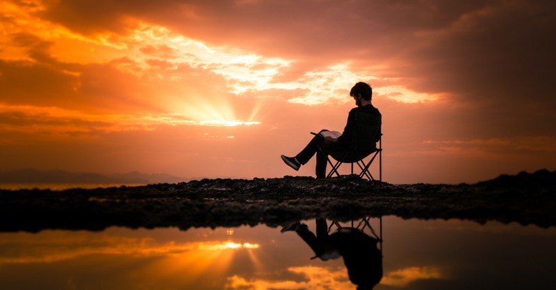 man sitting on camping chair at sunset quietness