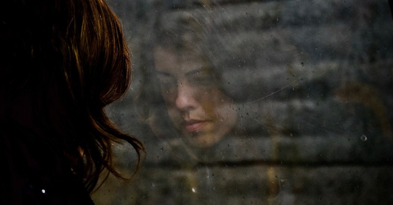 el reflejo de una mujer triste mirando por la ventana con gotas de lluvia, una oracion de fe cuando no hay mas lucha en ti 