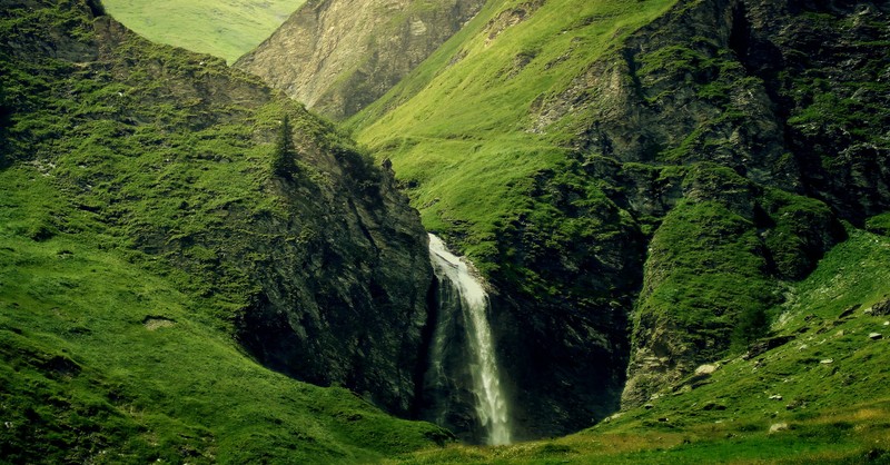 waterfall through green mountain valley