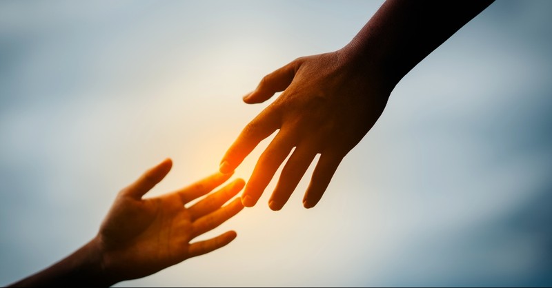 Hand grabbing another hand with a glowing light between