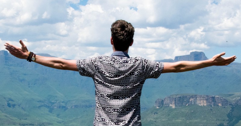 man with arms wide in praise and worship mountainscape