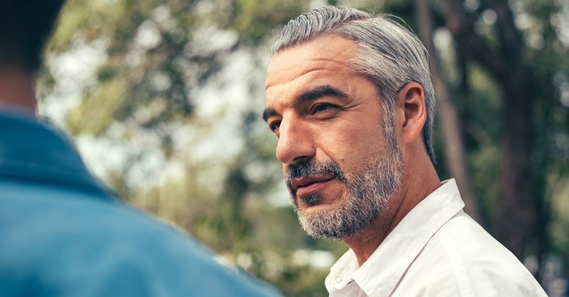 senior dad looking thoughtfully at adult son
