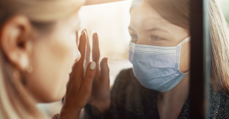 two women looking through window wearing face masks, seeing 2020 new lens