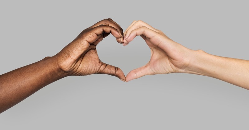 black and white hands making heart shape together