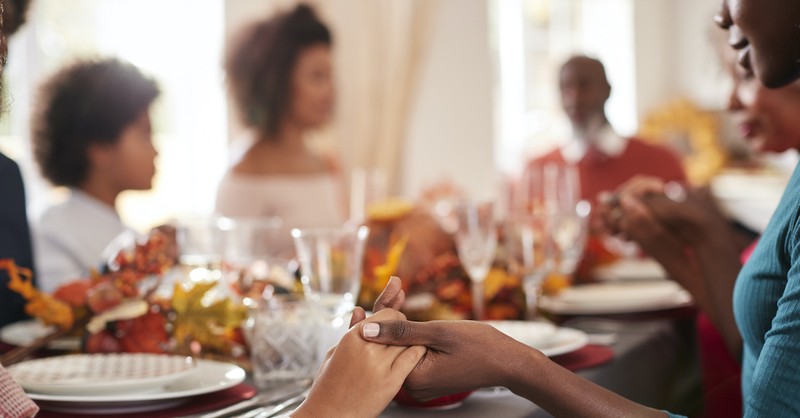 Group at the Thanksgiving dinner table, praying