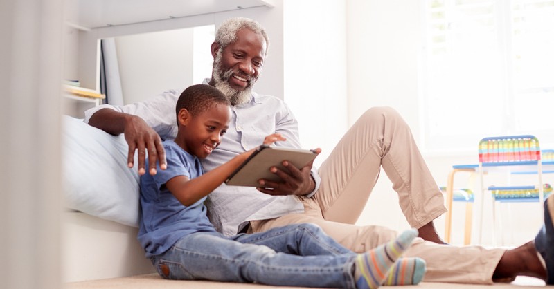 grandfather with kid looking at a tablet