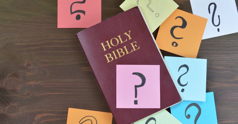 bible covered with post-it notes with question marks on them