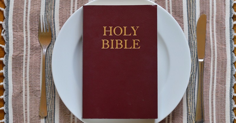 Bible on empty dinner plate on table