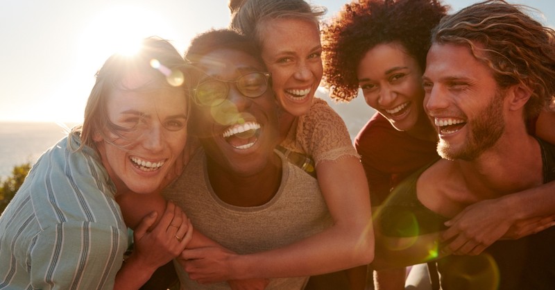 young group of friends laughing together with sun setting, songs to listen to when life is changing