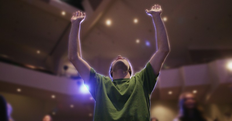 man in church arms up in prayer and praise