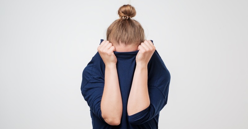 Embarrassed woman hiding her face, reasons you're stuck and how to break free