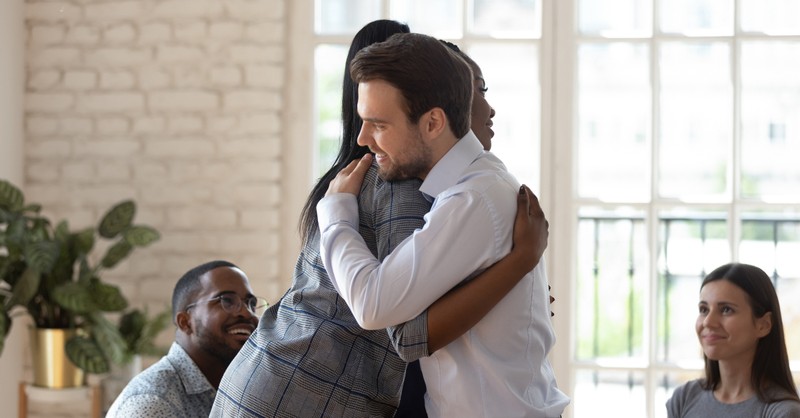 coworkers resolving conflict hugging