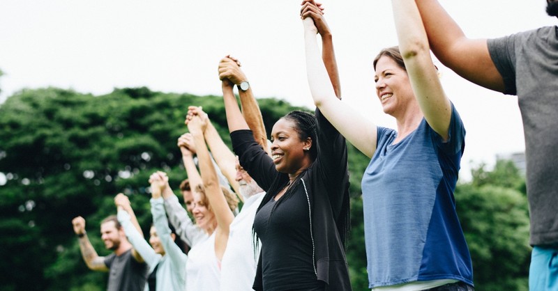 line of diverse people standing together holding raised hands, prayers for hidden strength