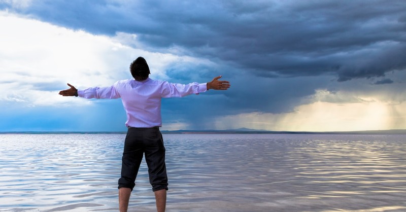 Man standing before a storm, questioning God